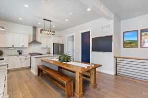 Elegant kitchen and dining space with granite countertops, premium gas range, tiled backsplash, and built-in microwave island. Seamless flow to a refined dining area with a statement farmhouse table