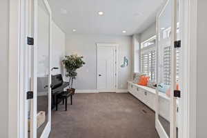 Versatile music room or office with elegant wooden shutters, a built-in window seat with storage, and a closet. Glass doors add a touch of openness while offering privacy when needed.