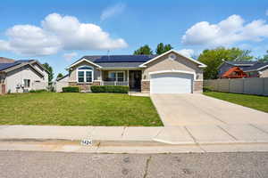 View of front of property with a porch, solar panels, a garage, driveway, and stucco siding