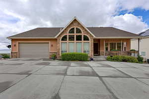 View of front of house featuring stone siding, driveway, stucco siding, a garage, and covered porch