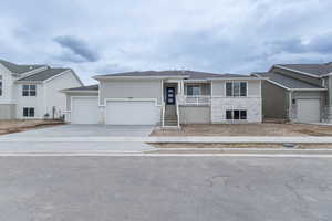 Single story home featuring an attached garage, concrete driveway, and stone siding