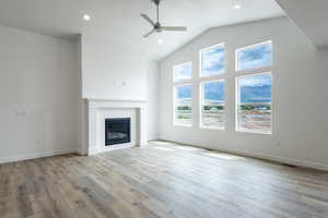 Unfurnished living room with ceiling fan, a glass covered fireplace, wood finished floors, recessed lighting, and baseboards