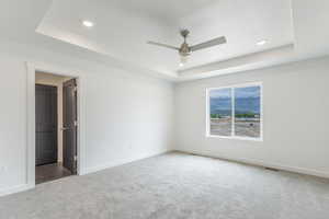 Carpeted spare room with a tray ceiling, ceiling fan, baseboards, and recessed lighting