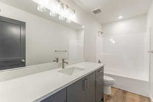 Full bathroom with toilet, vanity, shower / tub combination, and wood finished floors