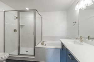 Full bathroom with toilet, vanity, a garden tub, and a marble finish shower