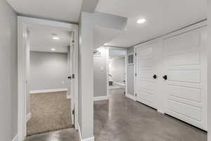 Hallway featuring baseboards, visible vents, concrete floors, and recessed lighting