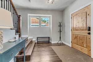Entryway featuring dark wood finished floors, baseboards, stairs, and a textured ceiling