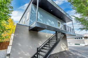 View of side of home with fence, stairway, and a balcony