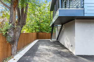 View of property exterior featuring stairway, a balcony, fence, and stucco siding