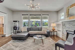 Living area with baseboards, a notable chandelier, wood finished floors, and a textured ceiling