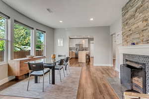 Dining space featuring a fireplace, baseboards, a textured ceiling, and light wood-style flooring