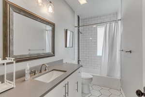 Full bath with toilet, vanity, tile patterned floors, and shower / bathtub combination with curtain