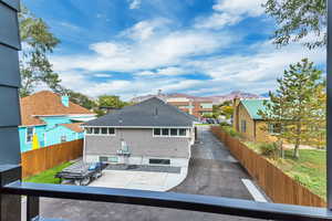 Back of property with a mountain view, fence, roof with shingles, and a residential view