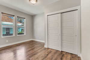 Unfurnished bedroom with baseboards, a closet, and dark wood finished floors