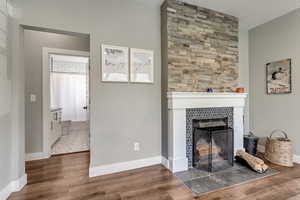 Living room featuring wood finished floors, a tiled fireplace, and baseboards