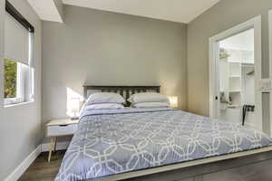 Bedroom featuring wood finished floors, a spacious closet, baseboards, and a closet