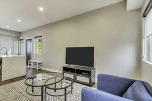 Living area with dark wood-style flooring, recessed lighting, and baseboards