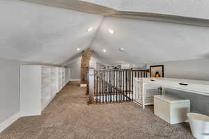Bonus room with baseboards, vaulted ceiling, carpet flooring, and a textured ceiling
