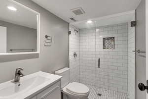 Full bath featuring toilet, vanity, visible vents, and a stall shower