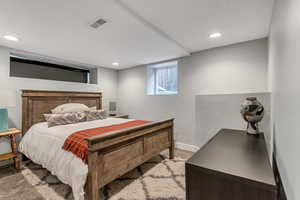 Carpeted bedroom with baseboards, visible vents, and recessed lighting