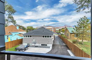 Back of property with a mountain view, fence, a shingled roof, and a residential view