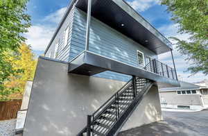 View of home's exterior featuring fence, stairway, and a balcony