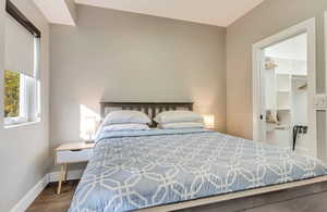 Bedroom featuring wood finished floors, a walk in closet, baseboards, and a closet