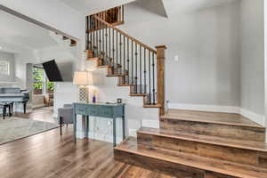 Staircase featuring wood finished floors, baseboards, and a textured ceiling