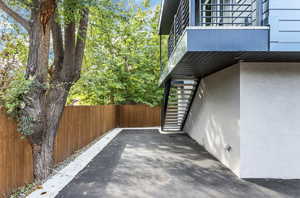 View of side of home with stairs, fence, a balcony, and stucco siding