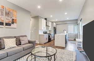Living room with light wood finished floors, recessed lighting, and baseboards
