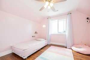 Bedroom with lofted ceiling, wood finished floors, baseboards, and a ceiling fan