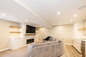 Living room featuring baseboards, recessed lighting, a fireplace, and light wood finished floors