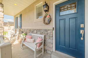 Property entrance featuring covered porch, stone siding, and stucco siding