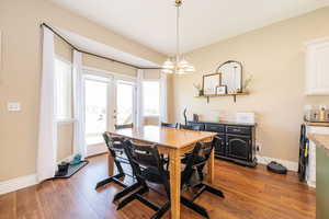 Dining room featuring dark wood-style floors, baseboards, a chandelier, and french doors