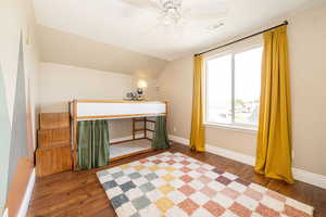 Bedroom featuring wood finished floors, vaulted ceiling, baseboards, and ceiling fan