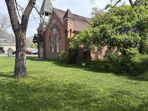 View of side of property with brick siding, a yard, and a shingled roof