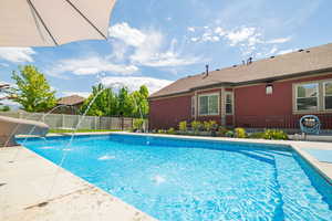 View of swimming pool featuring fence, a water slide, and a patio
