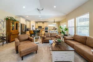 Living room featuring lofted ceiling, recessed lighting, and light colored carpet