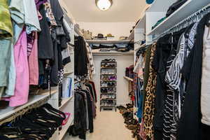 Spacious primary walk-in closet featuring carpet