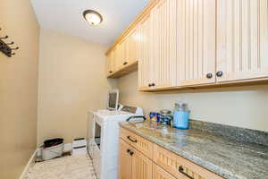 Clothes washing area featuring cabinet space, washer and clothes dryer, and baseboards