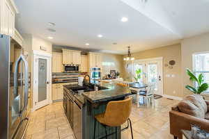Kitchen featuring appliances with stainless steel finishes, a sink, cream cabinetry, dark countertops, and healthy amount of natural light