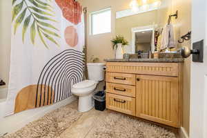 Full bath featuring toilet, vanity, and shower / bath combo with shower curtain