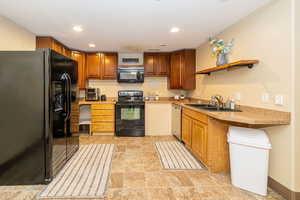 ADU Kitchen featuring black appliances, a sink, light countertops, recessed lighting, and brown cabinetry