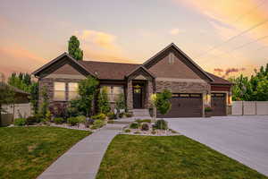 Craftsman-style house featuring stone siding, an attached garage, and driveway