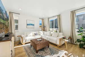 Living room with plenty of natural light, light wood-style floors, recessed lighting, and baseboards