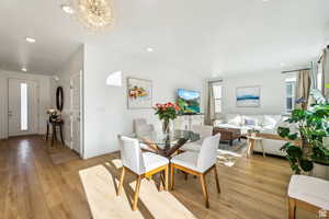 Dining space with a chandelier, light wood finished floors, recessed lighting, and baseboards