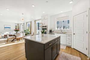 Kitchen with a sink, open floor plan, stainless steel double oven, white cabinetry, and decorative backsplash
