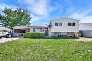 Split level home featuring roof mounted solar panels, an attached carport, and concrete driveway
