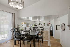 Dining area with light wood-style flooring, a chandelier, baseboards, and a fireplace