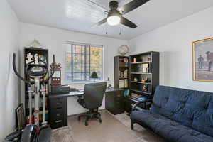 Carpeted office space featuring ceiling fan and baseboards